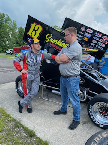 Tim Clagg talking with a sprint car driver in the pits before a dirt track feature