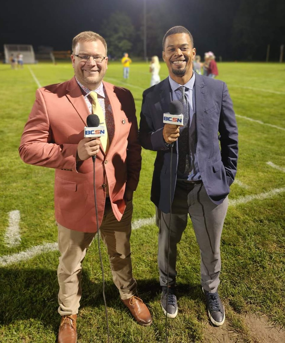 Tim Clagg and his BCSN partner with microphones on the field before a Friday night football game