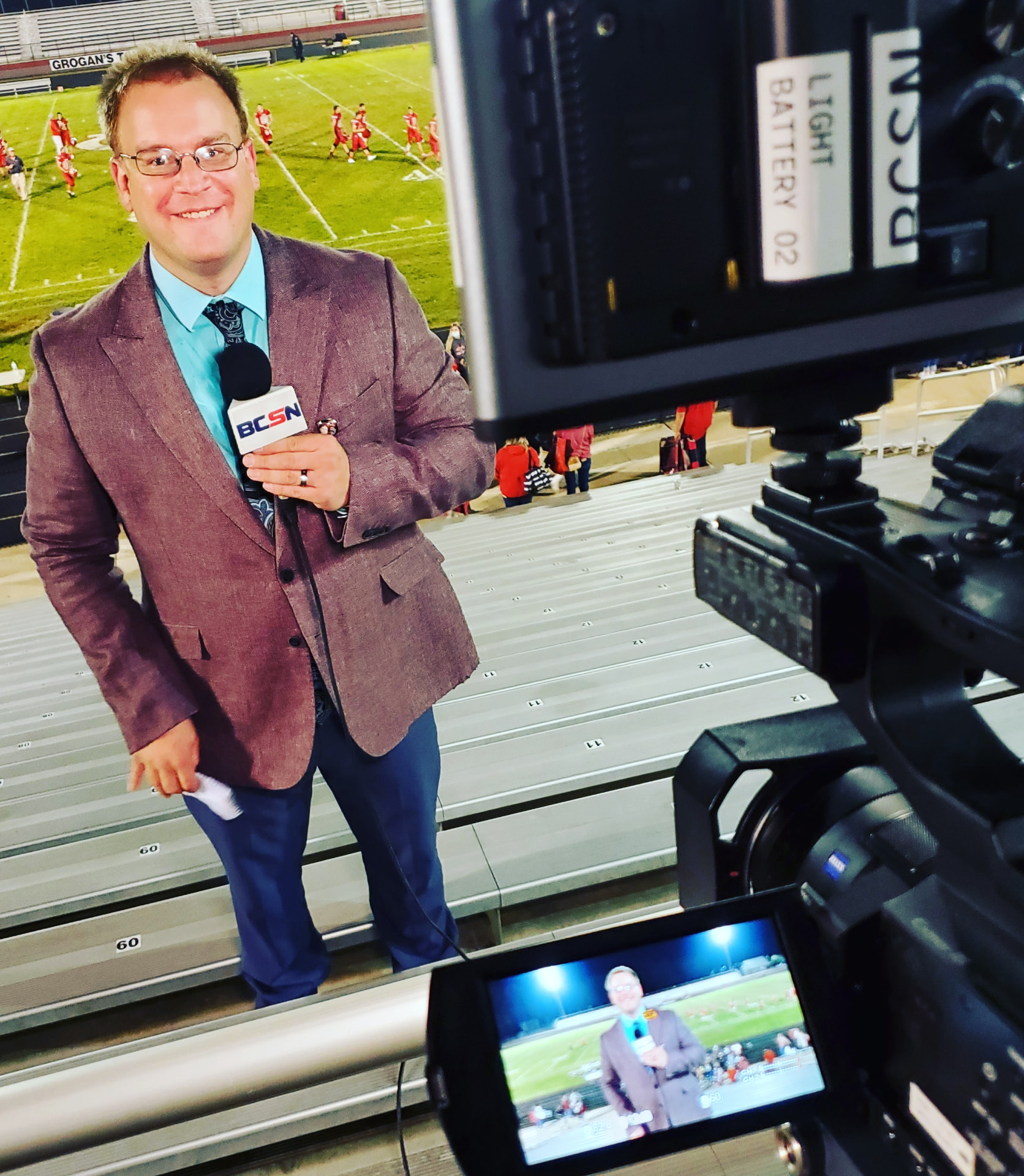 Tim Clagg standing in front of the camera on a stadium sideline platform
